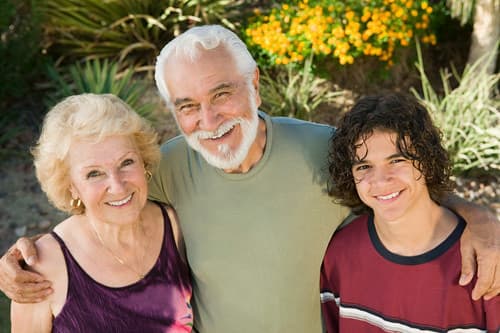 A smiling older couple spending time outdoors with their grandson